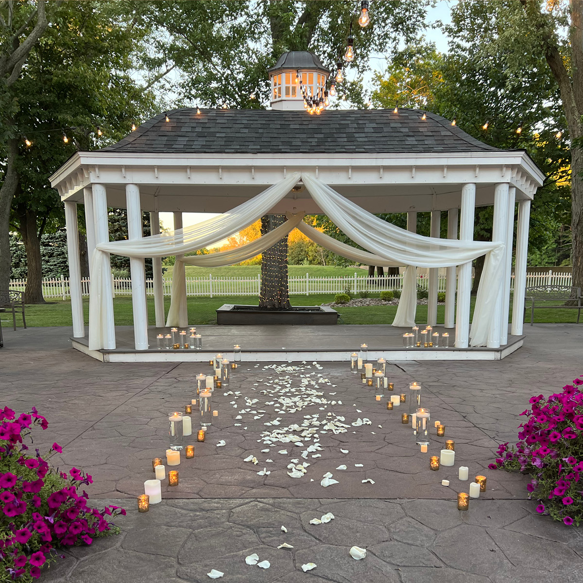 Patio gazebo with white curtains, candles, and string lights