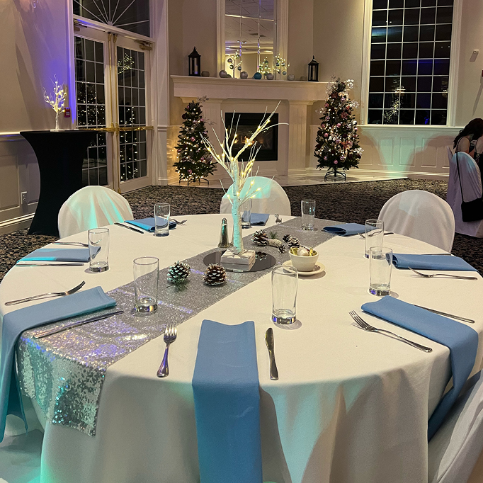 Banquet hall decorated for a holiday party with blue and white linens