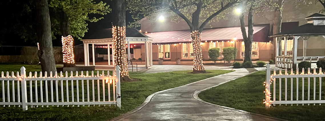 White picket fence with lights, gazebos and trees with trunk lights