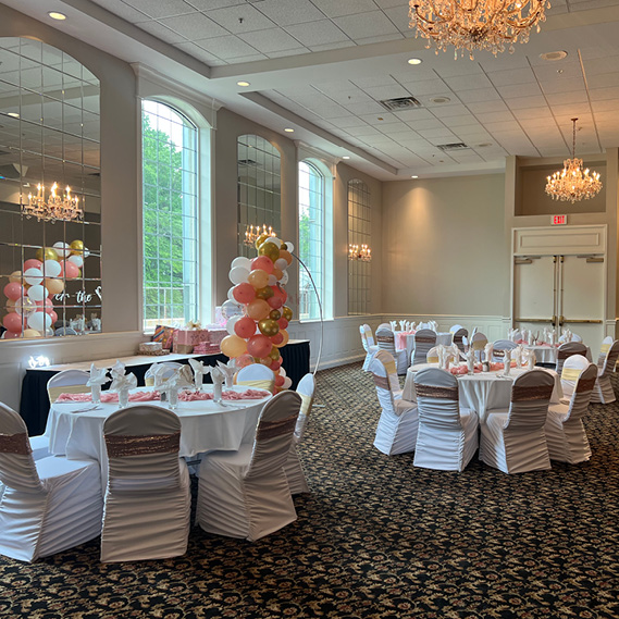 Banquet hall room decorated for a baby shower with pink and white balloons
